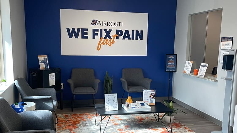 a photo of the lobby at Airrosti Carrollton. There is an Airrosti we fix pain fast poster on the wall