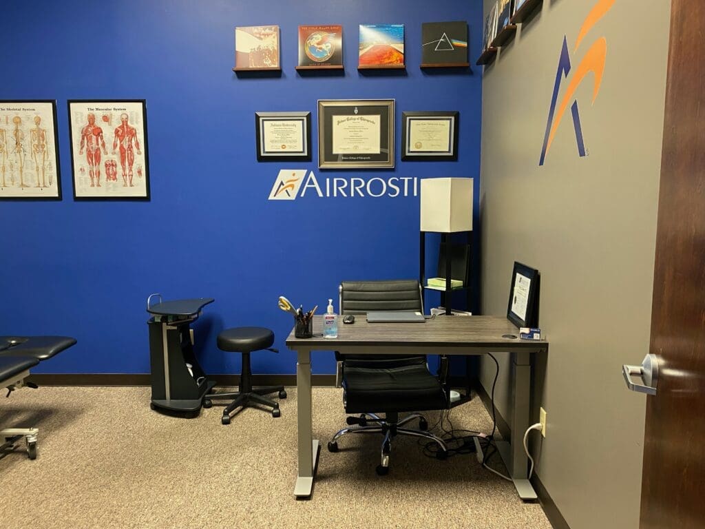 Photo of treatment room at Airrosti Far Hills. Included ACP's desk and accolades.
