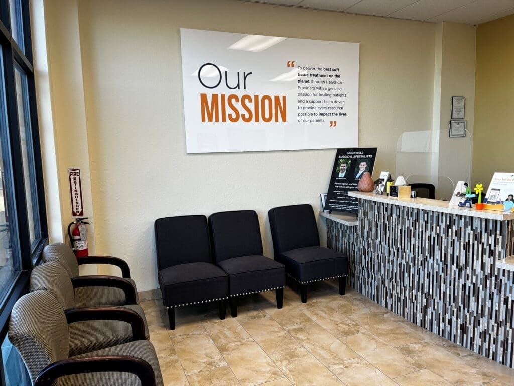 An interior view of the lobby at Airrosti Forney. The Airrosti mission statement poster is visible on the back wall.
