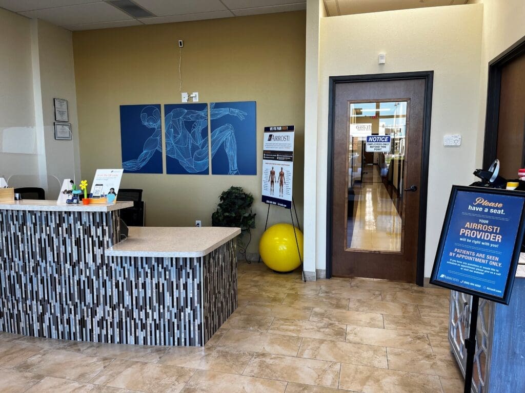 an interior view of the lobby at Airrosti Forney. The front desk and the interior door into the practice are both visible.