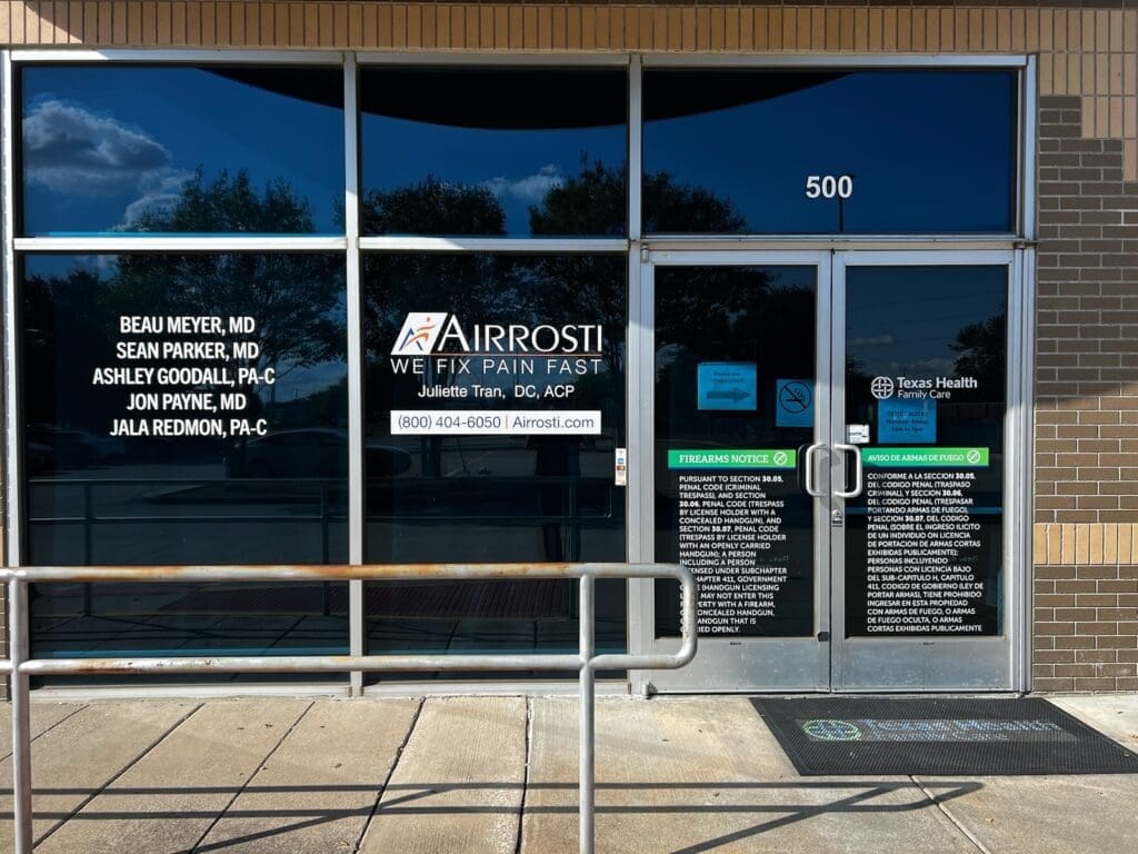Exterior entrance at Airrosti Rowlett. Airrosti branding is printed on glass window.