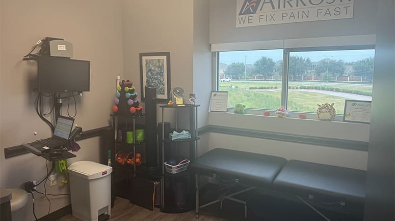 an interior photo of the recovery room at Airrosti South Grand Prairie. Exercise table and equipment are visible.