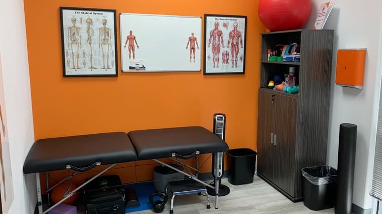 A view of the recovery room inside Airrosti Space Center. A treatment table and various exercise equipment are visible.