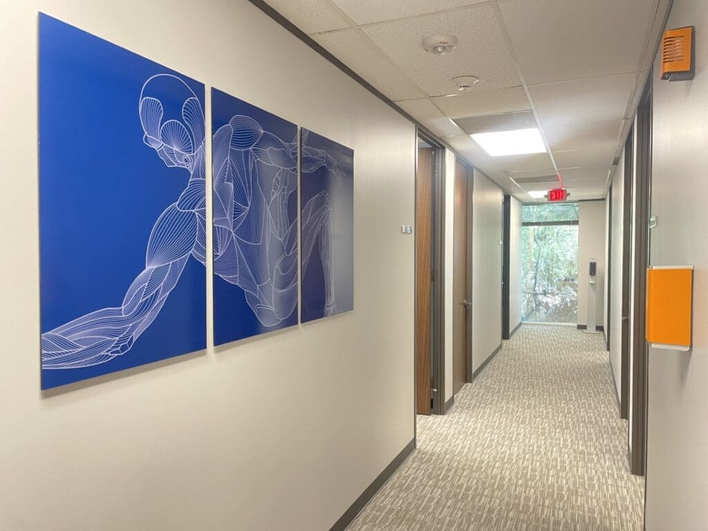 Interior hallway at Airrosti The Woodlands. Features Airrosti MSK art on the wall.