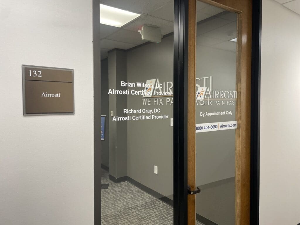 Interior entrance to Airrosti The Woodlands. Name plate and logo are printed on the glass window and door.
