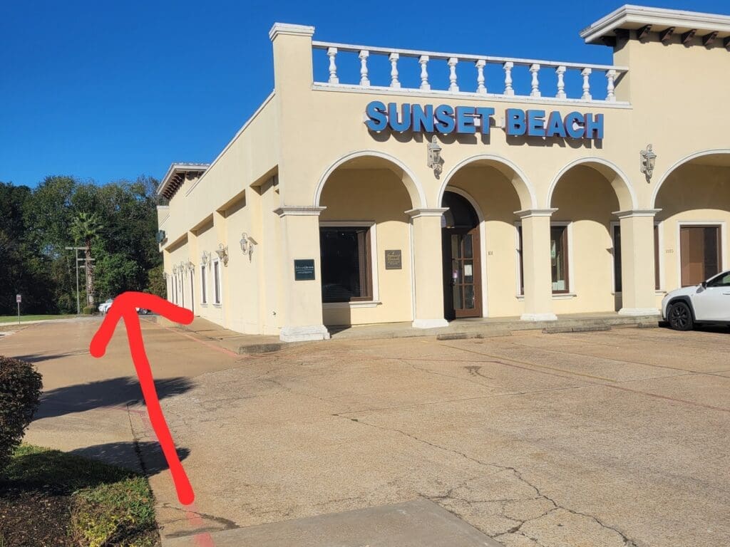 The exterior view of the building where Airrosti Nacogdoches is located. An arrow is directing the viewer where to park and enter.