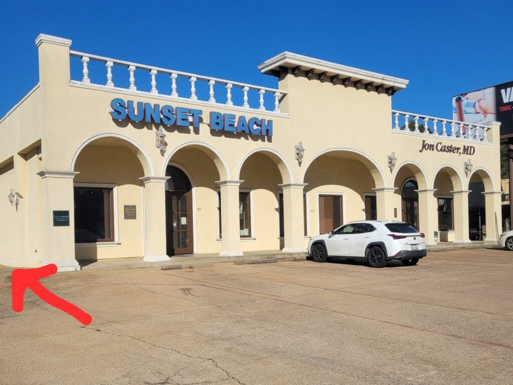The exterior view of the building where Airrosti Nacogdoches is located. An arrow is directing the viewer where to park and enter.